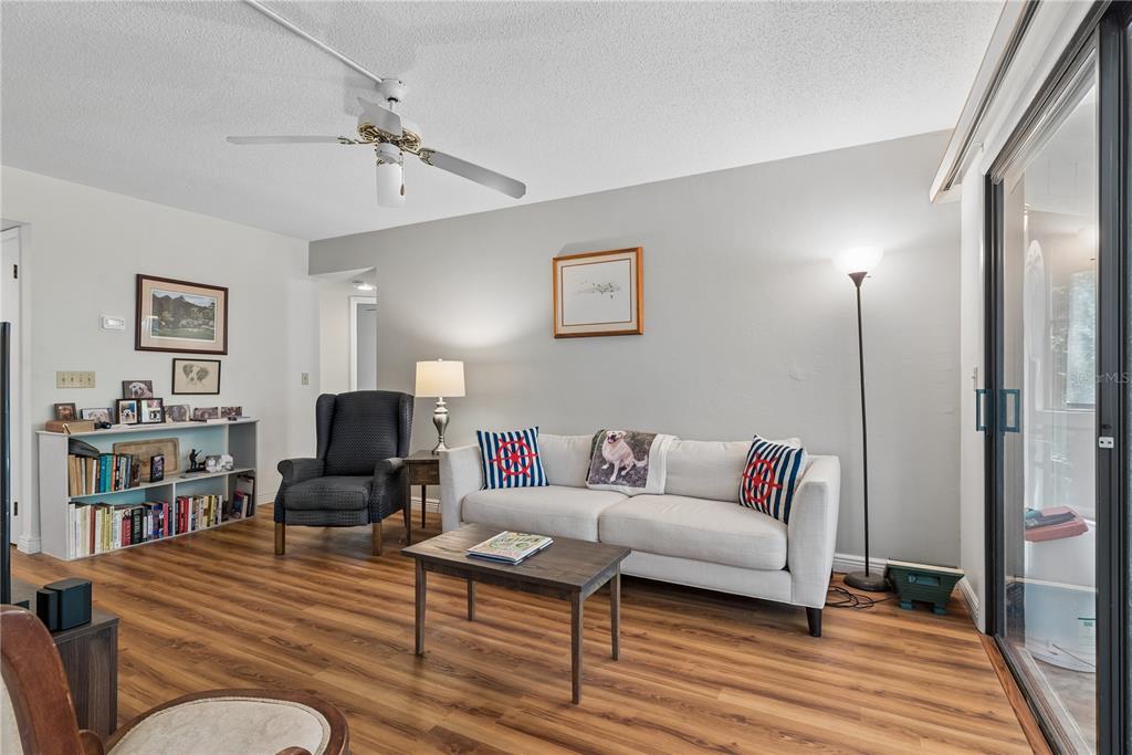 A living room features a white sofa, a dark armchair, a bookshelf, and wood-look flooring — 35 FAIRWAYS CIRCLE UNIT 35, PALM COAST, FL