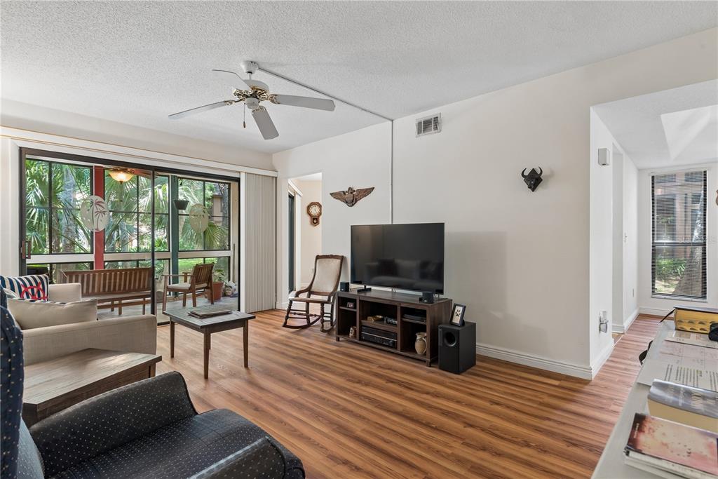 A living room features wood-look flooring, a ceiling fan, a television console, and sliding glass doors — 35 FAIRWAYS CIRCLE UNIT 35, PALM COAST, FL