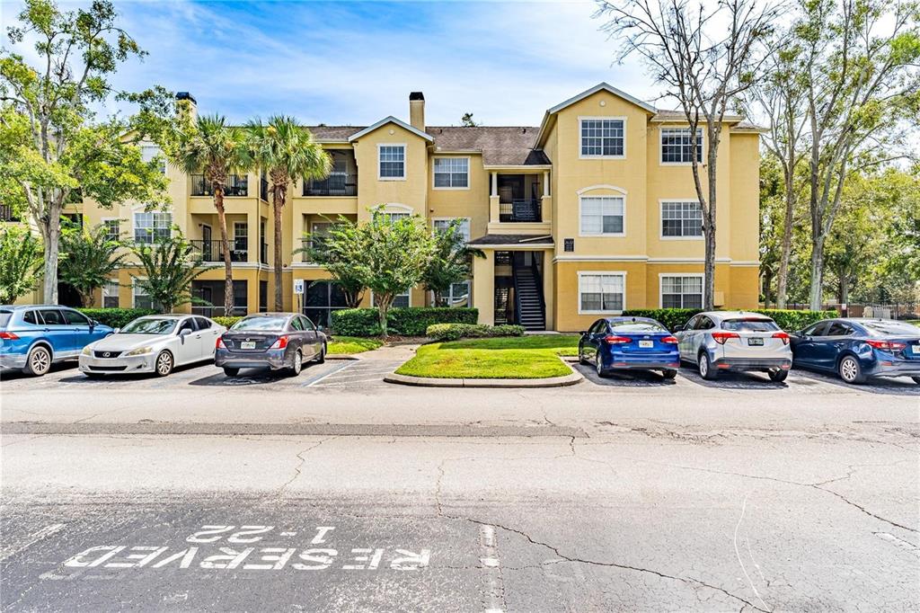 A three-story apartment building with yellow stucco walls and a parking lot in front — 2598 ROBERT TRENT JONES DRIVE UNIT 1027, ORLANDO, FL