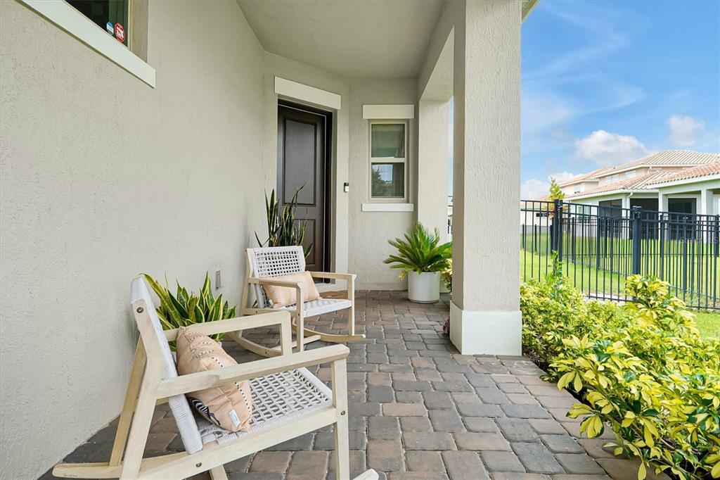 A covered patio features two rocking chairs, potted plants, and a paver floor — 13342 BROMBOROUGH DRIVE, ORLANDO, FL