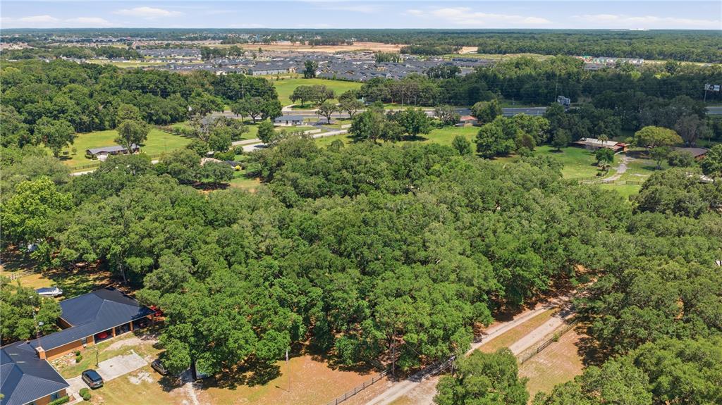 An aerial view shows a large, wooded property with a house and a gravel driveway — 7305 SW 86TH LANE, OCALA, FL