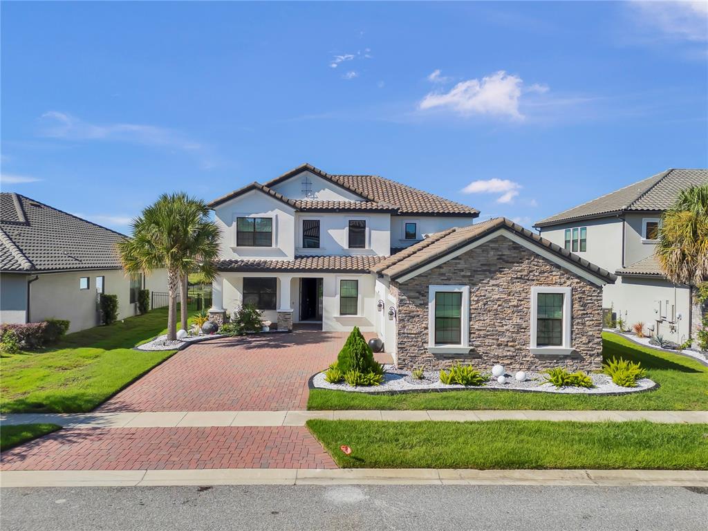 A two-story house with a stone facade, tile roof, and a brick-paved driveway — 2920 AGOSTINO TERRACE, KISSIMMEE, FL