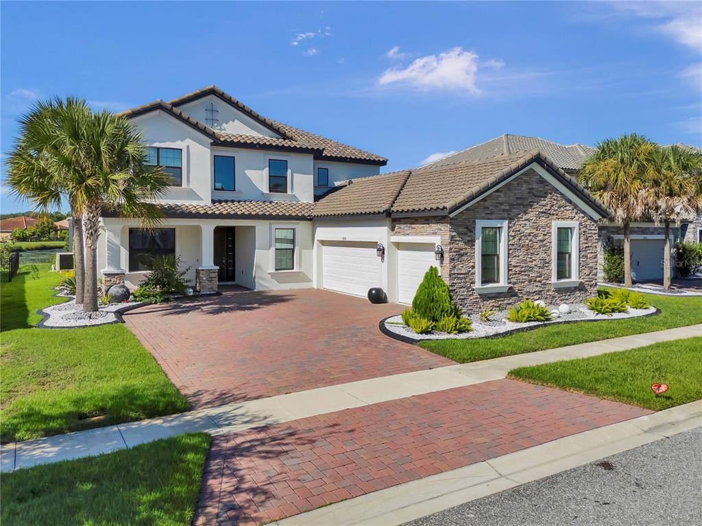 A two-story house with a brick driveway, stone facade, and a tiled roof — 2920 AGOSTINO TERRACE, KISSIMMEE, FL