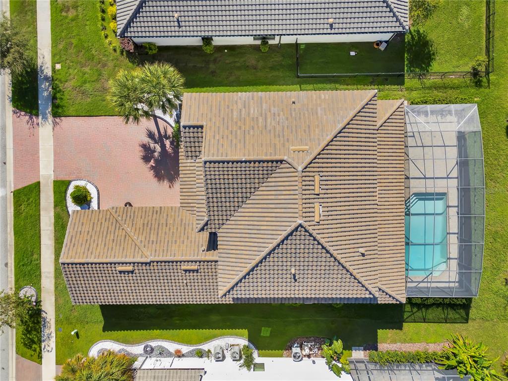 An aerial view shows a house with a tiled roof, a screened pool, and driveway — 2920 AGOSTINO TERRACE, KISSIMMEE, FL