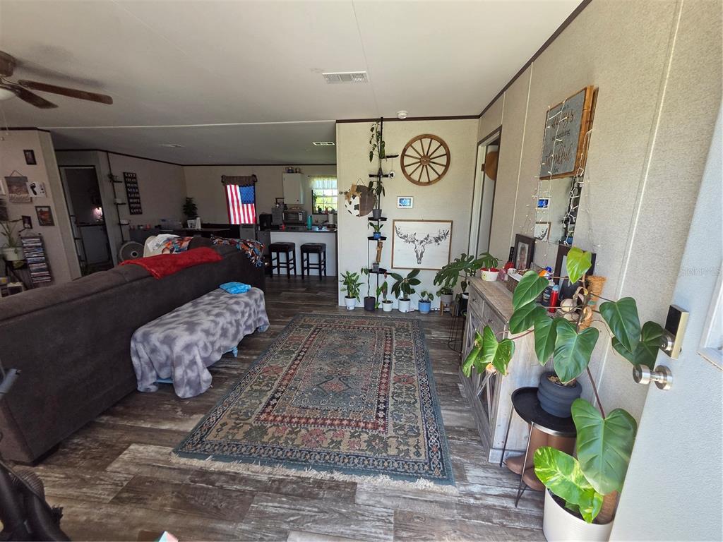 A living room features a large area rug, a sectional sofa, and a kitchen beyond — 1837 BLOSSOM COURT, PUNTA GORDA, FL