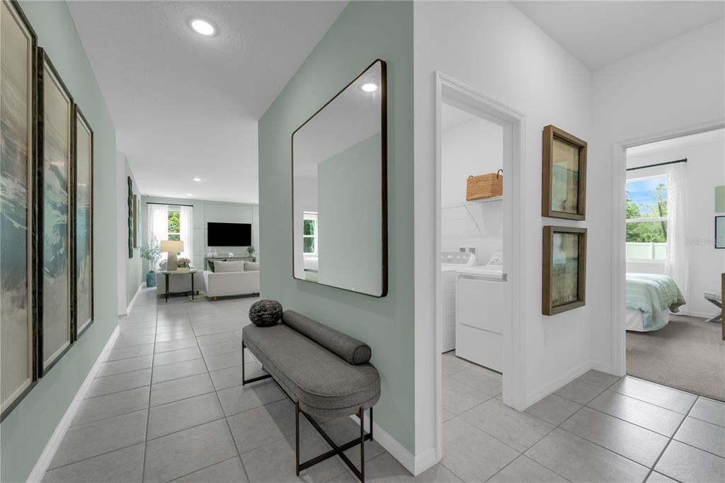 A hallway with tiled floors leads to a living area, featuring a bench and wall mirror — 3824 RISING TRAIL, DAVENPORT, FL
