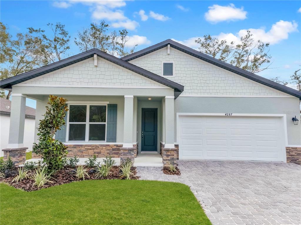 A single-story house with a stone-accented facade, a covered porch, and a two-car garage — 826 EMERALD GROVE DRIVE, APOPKA, FL