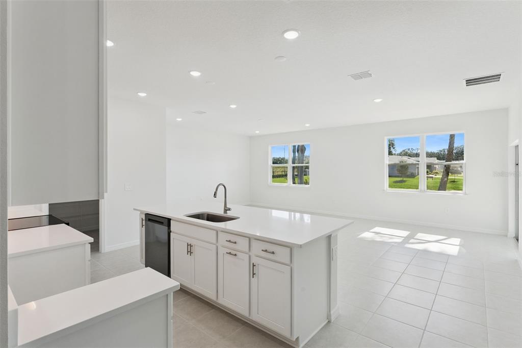 A white kitchen island with a sink sits in an open-concept room with tiled floors — 826 EMERALD GROVE DRIVE, APOPKA, FL