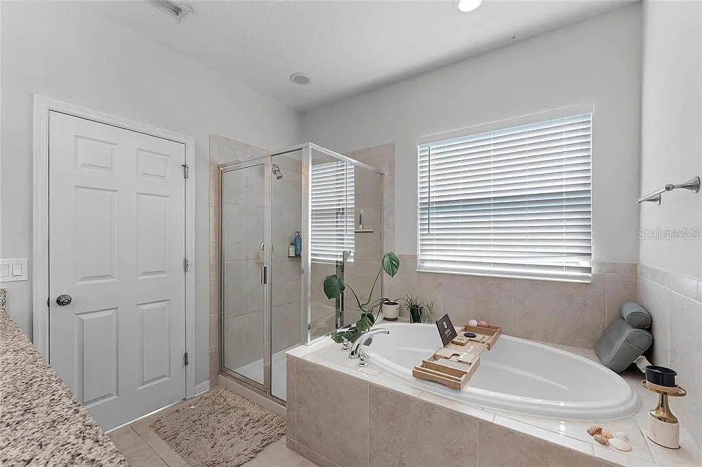 A bathroom features a tiled shower, a soaking tub with a wooden tray, and blinds — 3946 WIND DANCER CIRCLE, ST CLOUD, FL