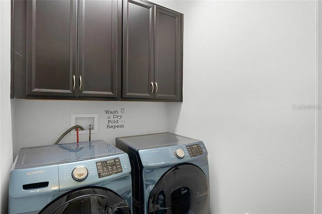 A laundry room features dark wood cabinets above a pair of blue Samsung appliances — 3946 WIND DANCER CIRCLE, ST CLOUD, FL
