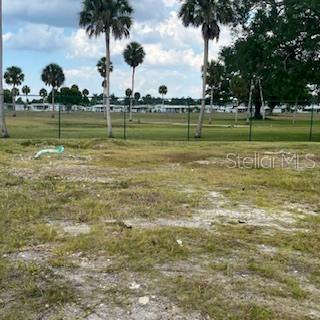 A vacant, grassy lot features scattered patches of sand and palm trees in the background — 4900 3RD A STREET E UNIT 613, BRADENTON, FL