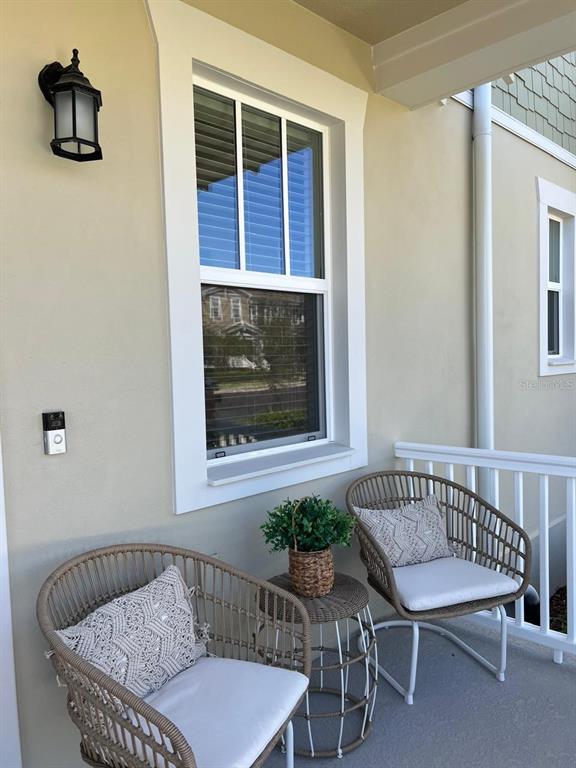 A covered porch features two wicker chairs, a small side table, and a window — 2252 CELEBRATION BOULEVARD, CELEBRATION, FL