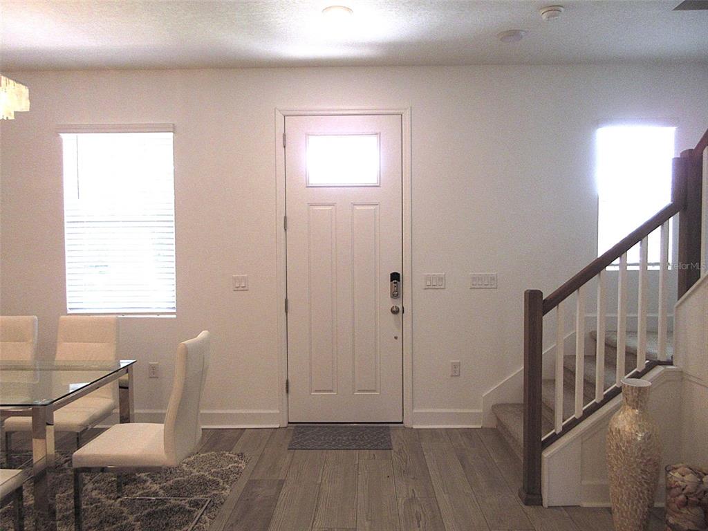 A dining area with a glass table, front door, and staircase with wooden railings — 2252 CELEBRATION BOULEVARD, CELEBRATION, FL