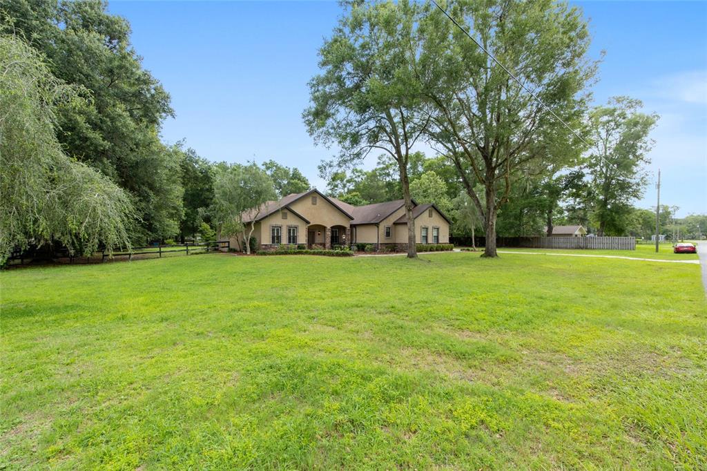 A single-story house with a tan exterior sits on a large, grassy lot with trees — 3 HIALEAH DRIVE, OCALA, FL