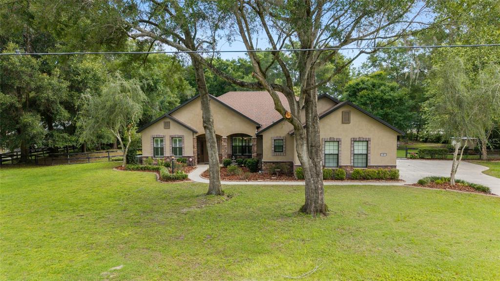 A single-story tan stucco house with a stone facade sits on a large grassy lot — 3 HIALEAH DRIVE, OCALA, FL
