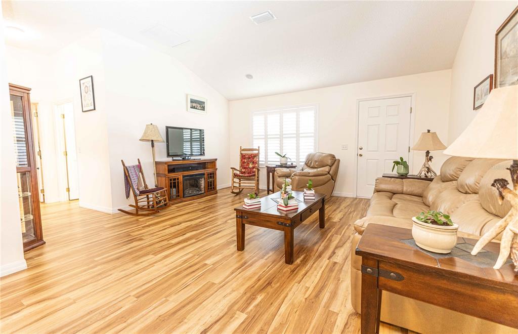 A dining room features wood-look flooring, a wooden table with chairs, and a matching hutch — 2706 MORVEN PARK WAY, THE VILLAGES, FL
