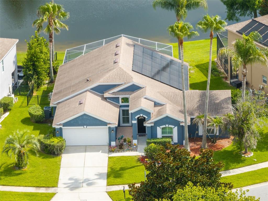 An aerial view of a blue house with a solar panel array on the roof — 216 TAVESTOCK LOOP, WINTER SPRINGS, FL