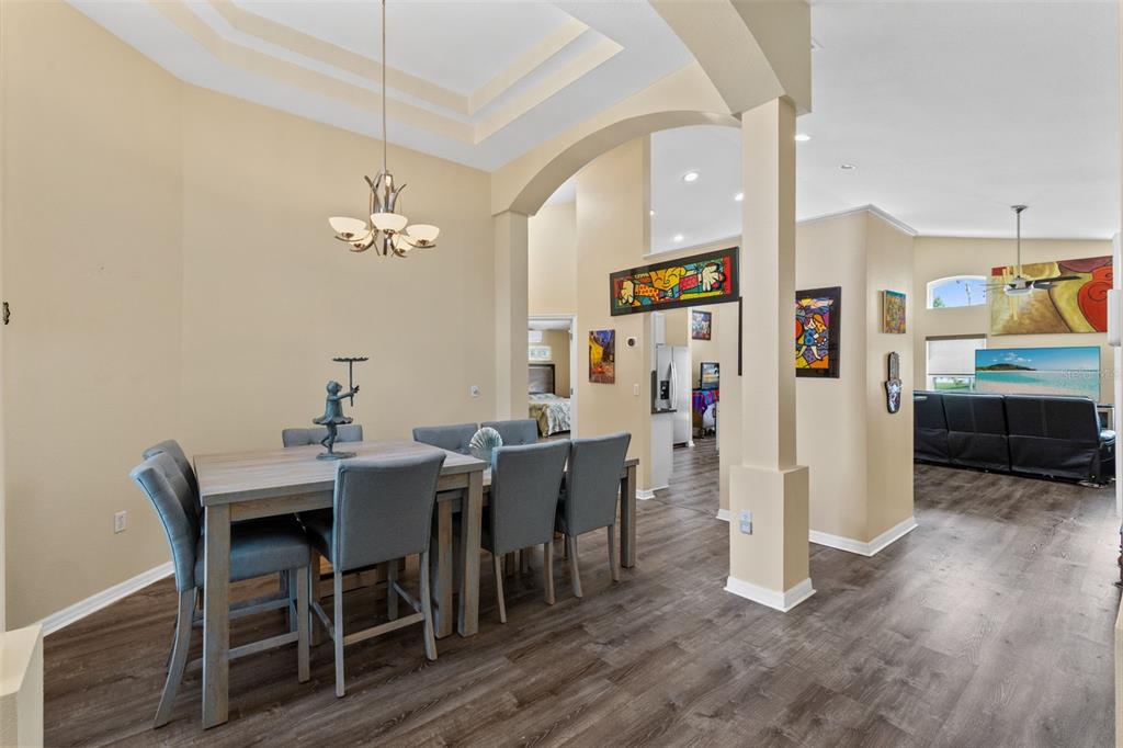 A dining area with a wooden table and gray chairs leads into a living room — 216 TAVESTOCK LOOP, WINTER SPRINGS, FL