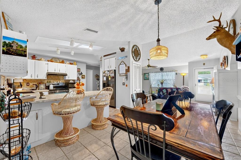 A kitchen with white cabinets and a breakfast bar opens into a dining area — 2956 BRISTOL LANE, SOUTH DAYTONA, FL