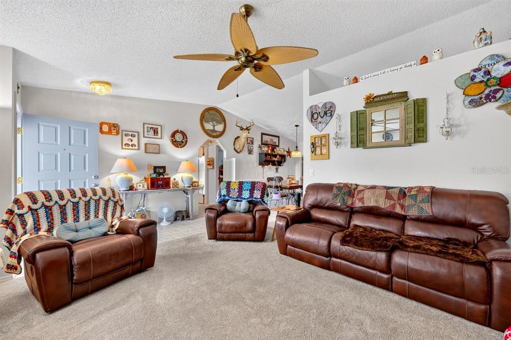 A living room features brown leather furniture, a ceiling fan, and various wall decorations — 2956 BRISTOL LANE, SOUTH DAYTONA, FL