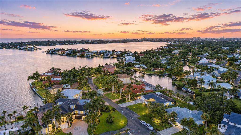 An aerial view of a waterfront residential neighborhood at sunset with palm trees and houses — 1761 SANDALWOOD DRIVE, SARASOTA, FL