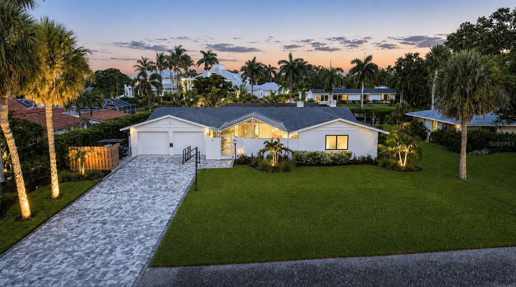 A white single-story house with a paved driveway, palm trees, and a green lawn — 1761 SANDALWOOD DRIVE, SARASOTA, FL