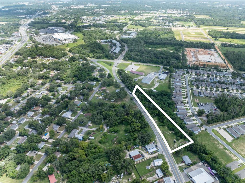 An aerial view shows a long, narrow, undeveloped plot of land outlined in white — 801 S DIXIE AVENUE UNIT A, FRUITLAND PARK, FL
