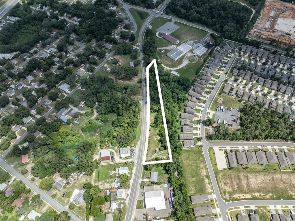 An aerial view shows a vacant, wooded lot outlined in white along a paved road — 801 S DIXIE AVENUE UNIT A, FRUITLAND PARK, FL