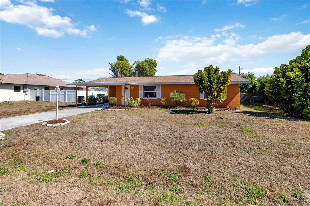 A single-story orange house with a carport and a large, dry front lawn — 3035 SHAMROCK DRIVE, VENICE, FL