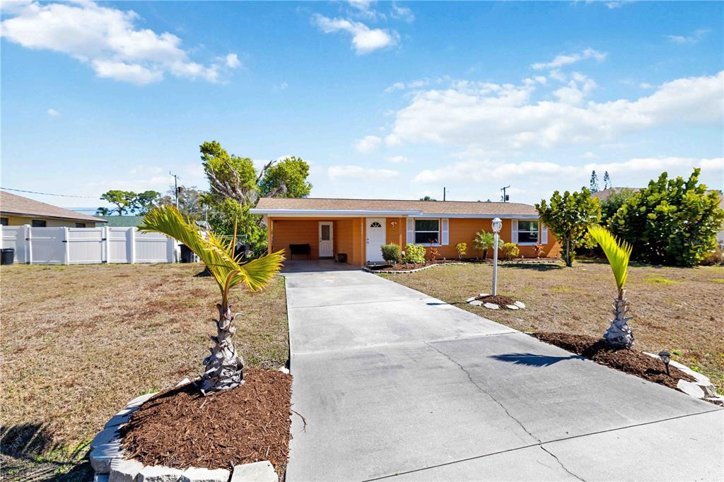A single-story orange house with a concrete driveway and two small palm trees — 3035 SHAMROCK DRIVE, VENICE, FL