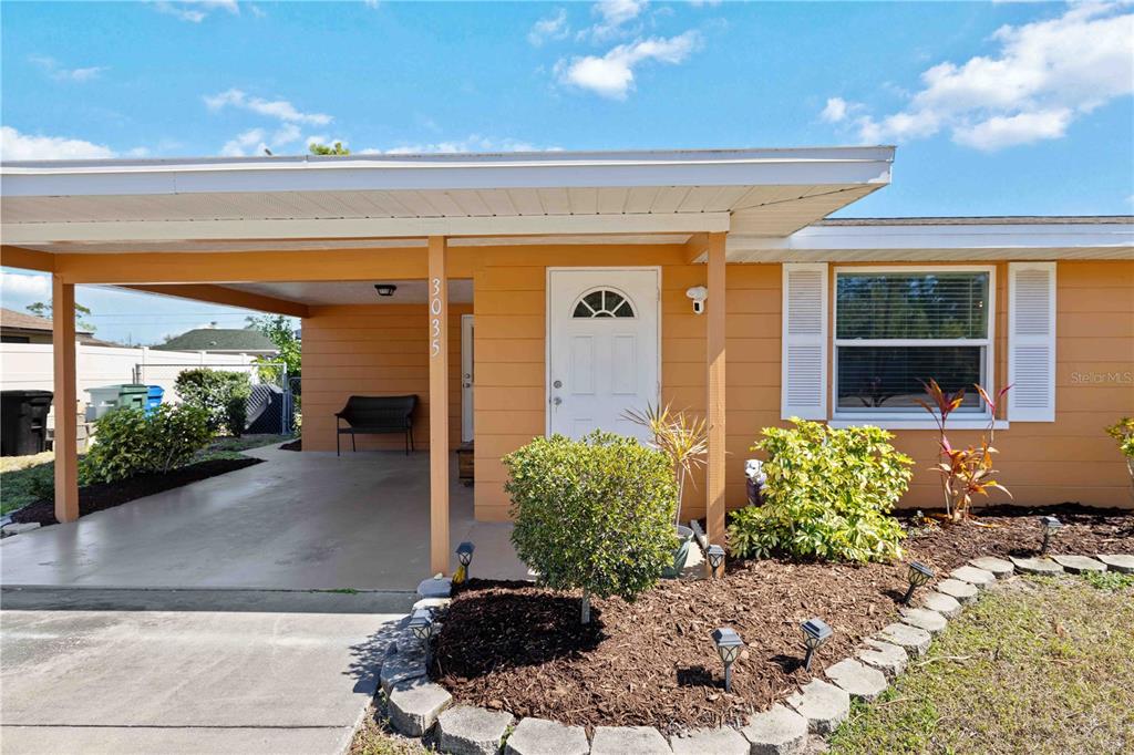 The exterior of a single-story house features an orange facade, a carport, and a front door — 3035 SHAMROCK DRIVE, VENICE, FL