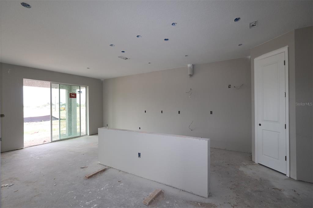 An unfinished kitchen features light gray cabinetry, a central island, and a sliding glass door — 5284 HIGH LINE DRIVE, ST CLOUD, FL
