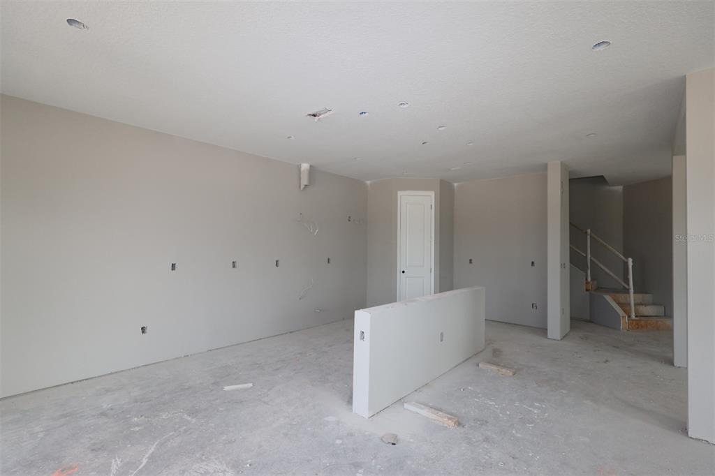 An unfinished kitchen with light gray cabinetry and a center island overlooks an open living area — 5284 HIGH LINE DRIVE, ST CLOUD, FL