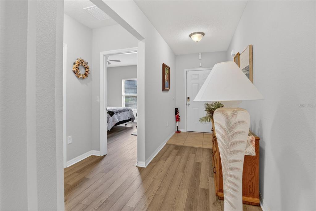 A hallway with wood-look flooring leads to an entryway with a white door — 255 HAINES BOULEVARD, WINTER HAVEN, FL
