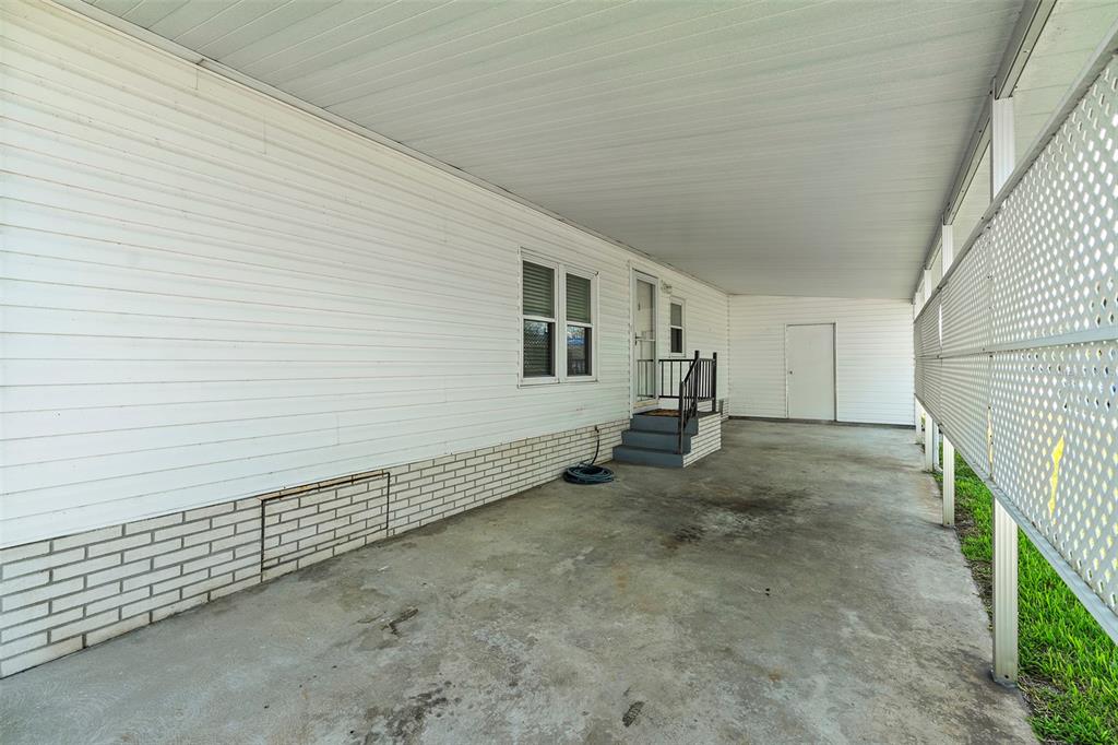 A covered concrete carport area alongside a white siding house with a small staircase — 2519 INDEPENDENCE LN, ST CLOUD, FL