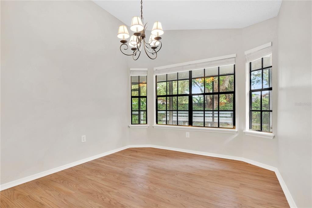 An empty dining room with wood-look flooring, a chandelier, and a bay window — 2141 WEKIWA OAKS DRIVE, APOPKA, FL