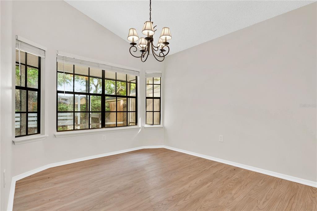 An empty dining room features light wood-look flooring, a chandelier, and large windows — 2141 WEKIWA OAKS DRIVE, APOPKA, FL