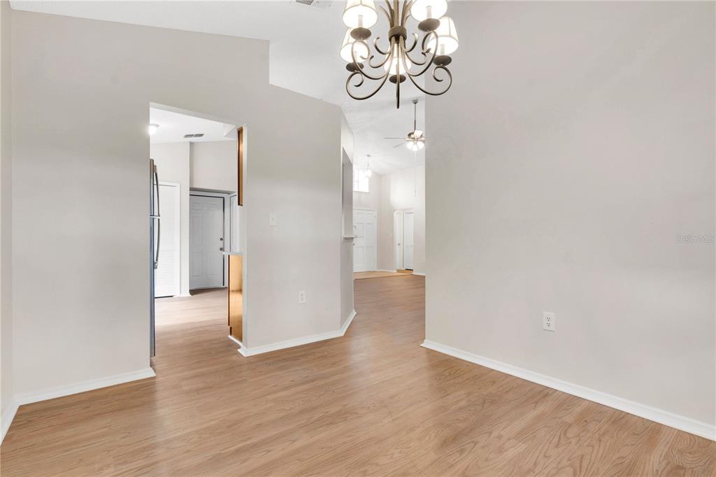 A dining area with light wood flooring, a chandelier, and views into adjacent rooms — 2141 WEKIWA OAKS DRIVE, APOPKA, FL