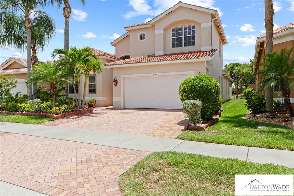 A two-story suburban house with a beige stucco exterior and a brick paver driveway — 5044 SANDY BROOK CIRCLE, WIMAUMA, FL