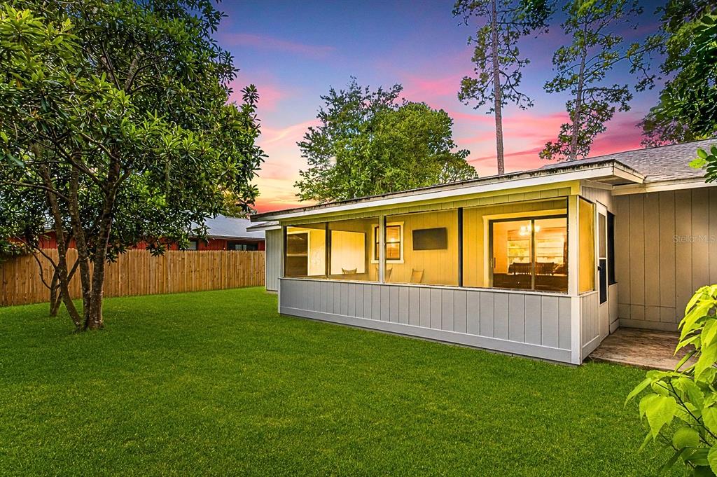A backyard view of a house with a screened-in porch and a wooden fence — 2627 UNITY TREE DRIVE, EDGEWATER, FL