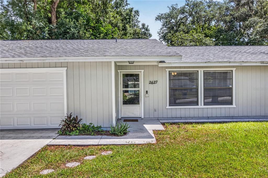 The exterior of a single-story house features light gray siding, a garage, and a front entrance — 2627 UNITY TREE DRIVE, EDGEWATER, FL