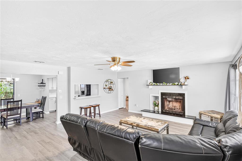 A living room with gray wood-look flooring, a fireplace, and a ceiling fan — 2627 UNITY TREE DRIVE, EDGEWATER, FL