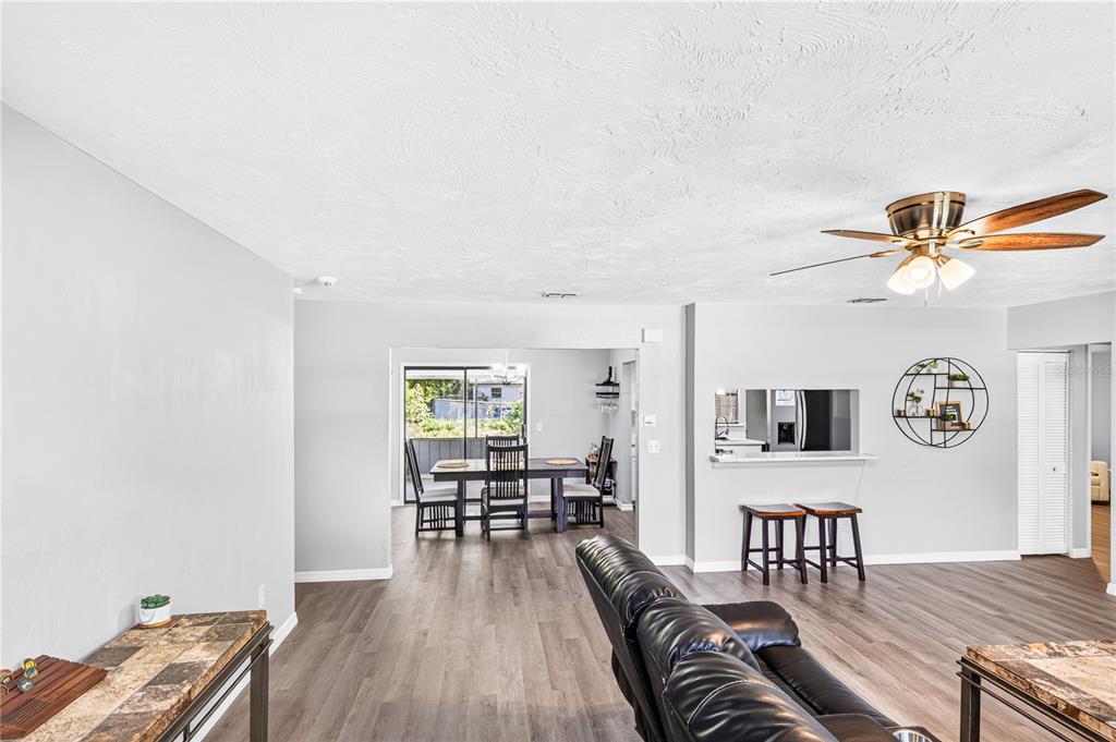 A living room with wood-look flooring, a ceiling fan, and an open view to the dining area — 2627 UNITY TREE DRIVE, EDGEWATER, FL