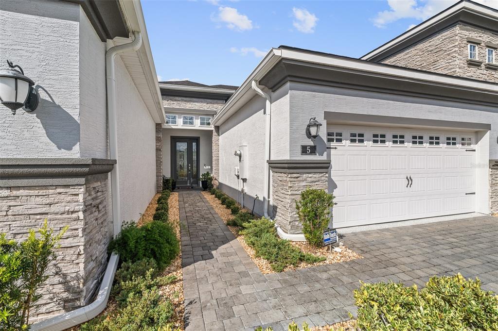A paved walkway leads to the front entrance of a house with a stone-accented garage — 5 LONGRIDGE LANE, ORMOND BEACH, FL