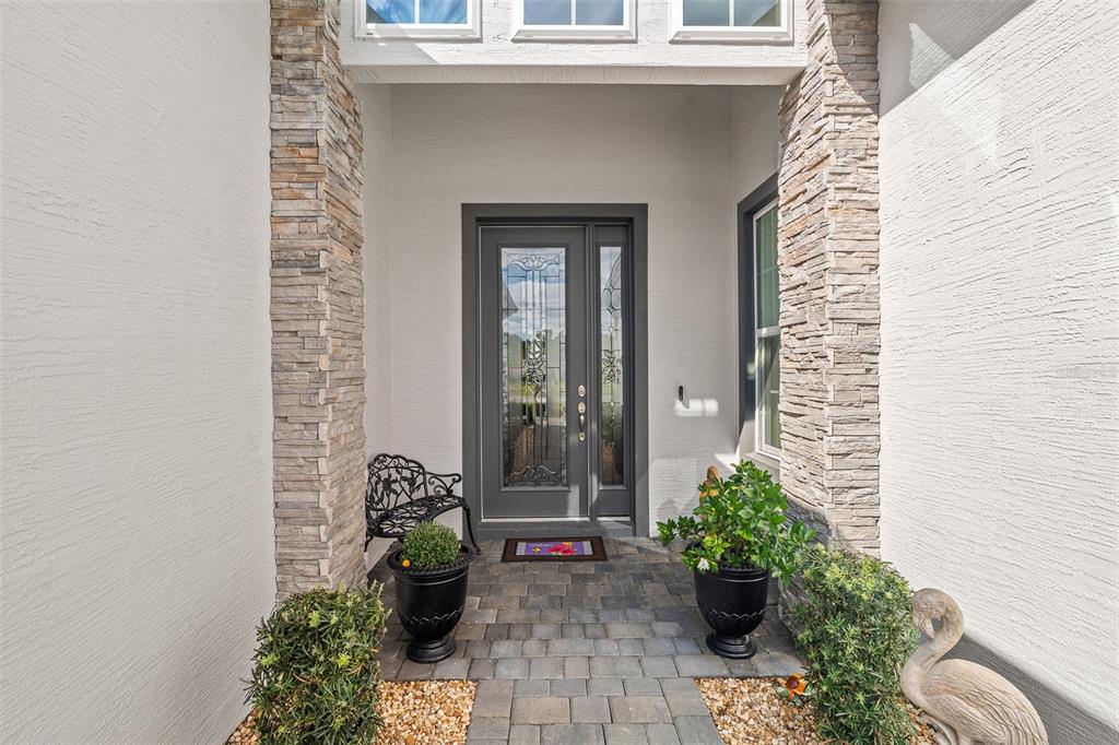 A front entryway features a dark gray door with glass panels, stone columns, and pavers — 5 LONGRIDGE LANE, ORMOND BEACH, FL