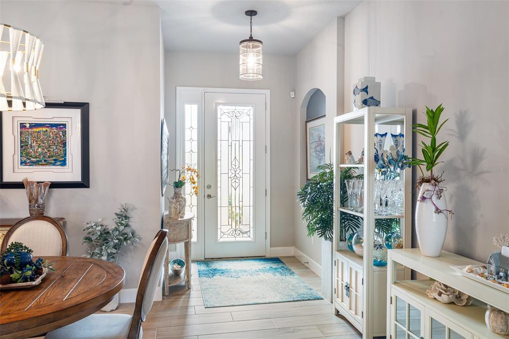 A bright entryway features a glass-paneled front door, tile flooring, and a decorative pendant light — 5 LONGRIDGE LANE, ORMOND BEACH, FL