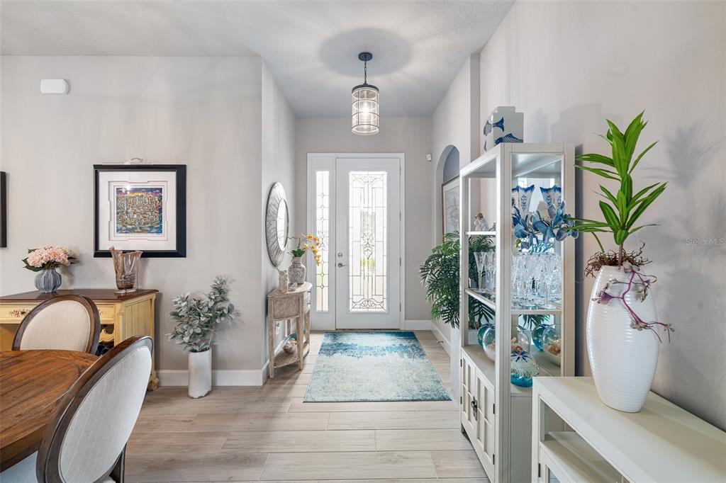 An entryway features light wood-look tile flooring, a glass-paneled front door, and a display cabinet — 5 LONGRIDGE LANE, ORMOND BEACH, FL