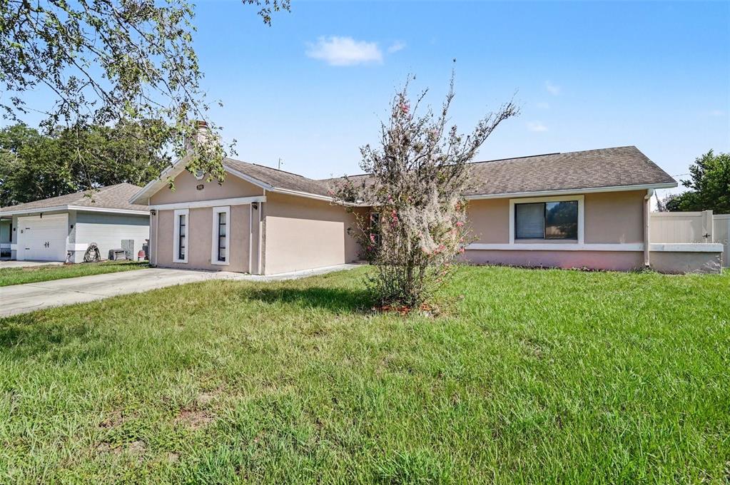 A single-story tan house with a concrete driveway and a front lawn under a blue sky — 510 WAVECREST DRIVE, ORLANDO, FL