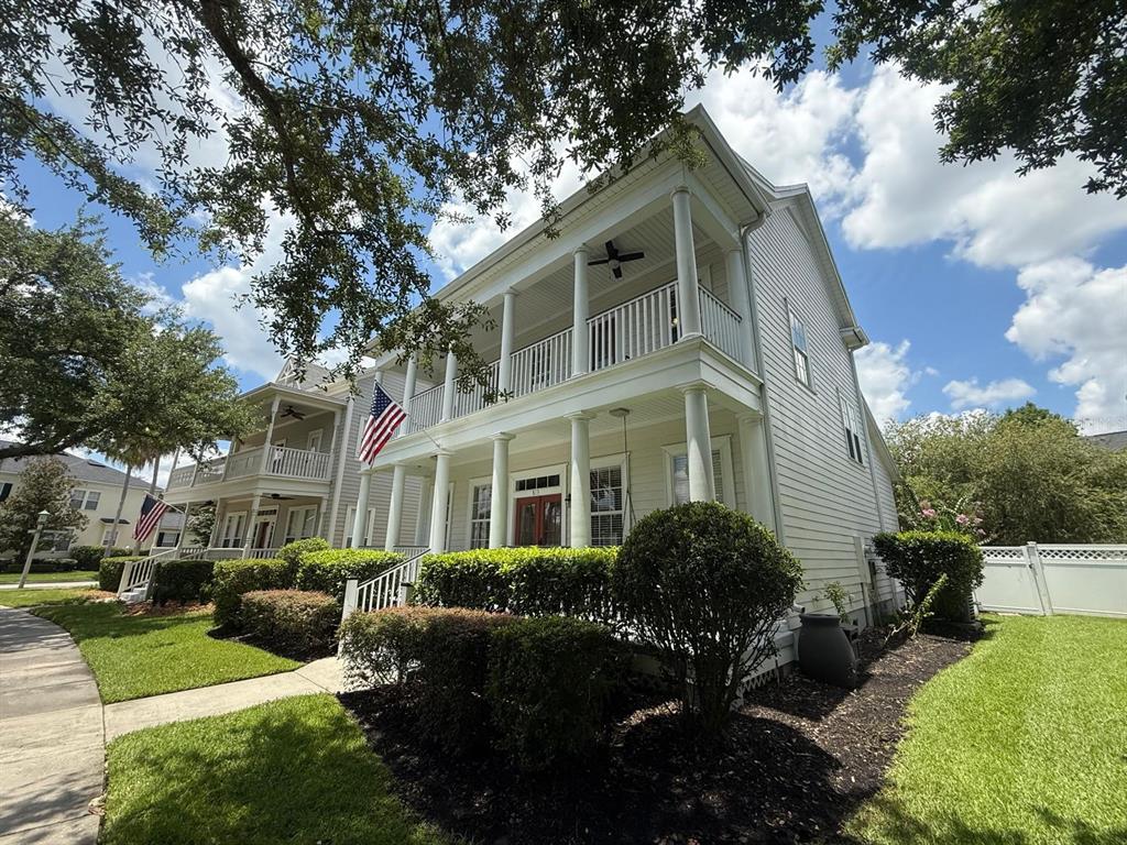 A two-story house with white siding, a front porch, and a second-story balcony — 813 OAK SHADOWS ROAD, CELEBRATION, FL
