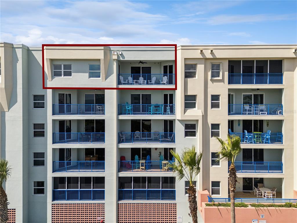 The exterior of a multi-story apartment building features balconies with blue railings and chairs — 5300 S ATLANTIC AVENUE UNIT 13-604, NEW SMYRNA BEACH, FL